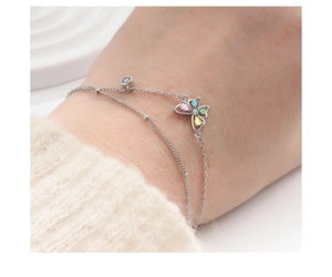 Detail eines doppellagigen Silberarmbands mit buntem Kristall Schmetterlingsanhänger