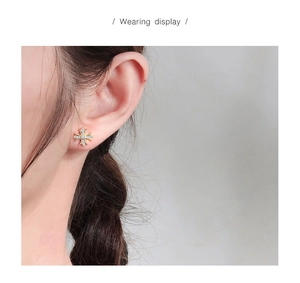Gros plan d'un clou d'oreille croix dorée avec diamants porté à l'oreille en détail