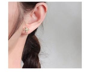 Gros plan de boucles d'oreilles croix en argent 925 doré avec zircons sur l'oreille