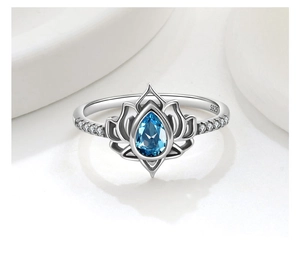 Vista macro di anello loto in argento 925 con zircone blu a goccia e marchio S925 inciso