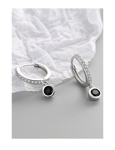 Détail de boucles d'oreilles huggie en argent S925 avec pierres claires et pendentifs noirs
