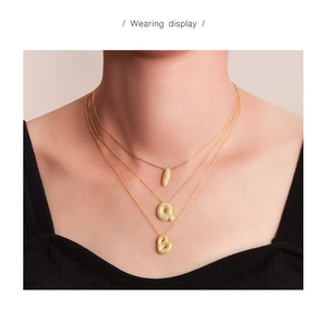 Close-up of triple-layered gold bubble letter necklaces with sparkling zircon pavé