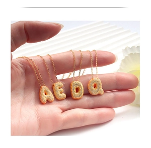 Macro shot of 18k gold plated bubble letter pendants with sparkling micro-pave zircons