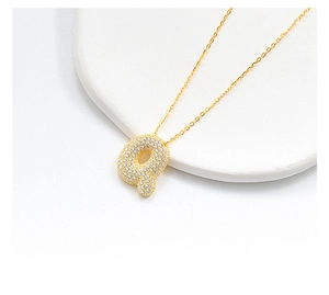 Macro view of golden bubble letter Q necklace pendant paved with sparkling small crystals