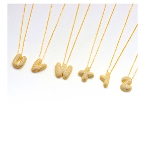Macro shot of 3D bubble letter pendants U-Z with cubic zirconia in gold plating