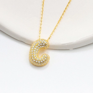 Detailed view of bubble initial C pendant with pavé cubic zirconia on gold necklace chain