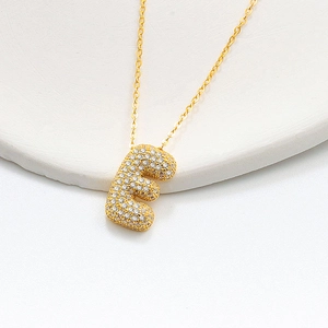 Macro shot of gold 3D bubble letter E pendant necklace with sparkling micro-pave crystals