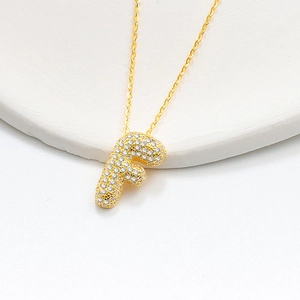 Macro detail of the gold-plated letter F bubble pendant necklace with pavé zircon