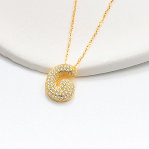 Detail of 3D bubble letter G pendant with full pave diamonds and gold chain