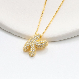Macro shot of S925 silver golden puffer letter K necklace with crystal pave setting