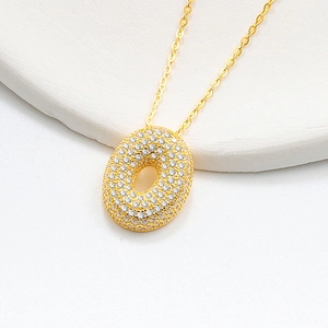 Macro shot of bubble letter gold pendant with pavé set white cubic zirconia stones