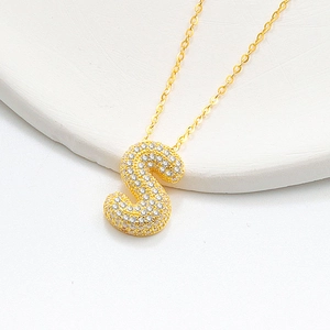 Close-up of a gold 3D puffy S-letter bubble necklace pendant with full pavé crystals