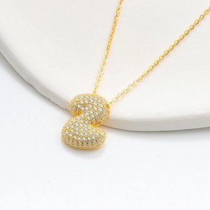 Macro shot of 925 silver golden puffy letter S pendant with iced out pavé zircon stones
