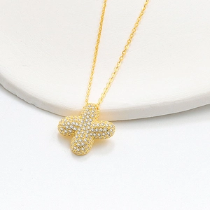 Macro shot of gold S925 silver necklace featuring a sparkling diamond-paved clover pendant