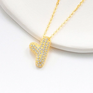 Macro view of golden S925 silver bubble letter Y pendant with pavé set crystals