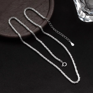 Macro detail of S925 sterling silver crushed silver chain with spring clasp and tag
