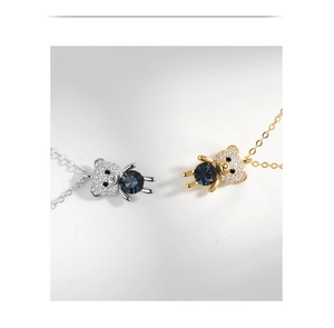 Detailed view of silver and gold bear pendants with blue crystals and pavé diamonds