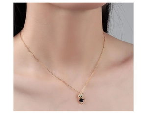 Close-up of elegant gold teddy bear pendant with blue crystal on a female model