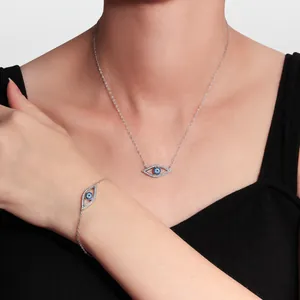 Detailed view of silver evil eye necklace and bracelet set with blue crystals on model