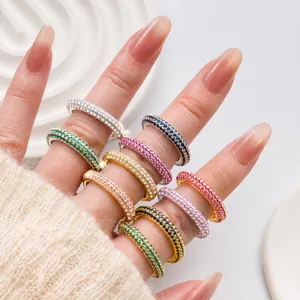Macro detail of multi-color micro-pave cubic zirconia eternity rings stacked on finger