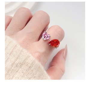 Detail of adjustable silver ring featuring pink heart and red pear-cut crystals on hand