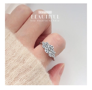 Dettaglio ravvicinato di un anello a tre pietre in argento 925 con moissanite al dito