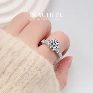 Detailed view of luxury S925 silver six-prong moissanite ring with side stones on a finger