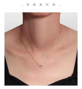 Gros plan d'un collier œil protecteur en argent S925 doré avec pierres turquoise sur modèle