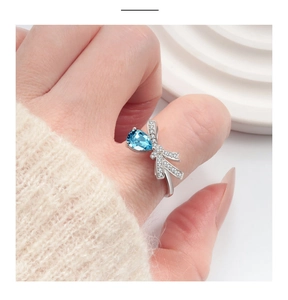 Gros plan détaillé d'une bague nœud en argent S925 avec pierre bleue sur la main du modèle