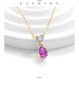 Macro detail of a heart-shaped white zircon and a pear-cut pink stone on a gold necklace