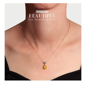 Detail of pear-cut yellow gemstone and heart zircon on a gold necklace worn by a model