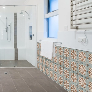 Detail of vintage mandala tile stickers with orange and blue floral pattern on bathroom wall