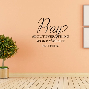 Detail of Pray About Everything vinyl wall decal on a warm peach background with a plant