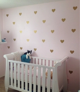 Detailed view of matte gold vinyl heart wall stickers arranged on a pink nursery wall