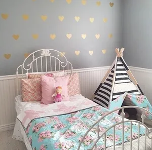 Detailed view of golden heart wall stickers and floral bedding in a cozy kids room