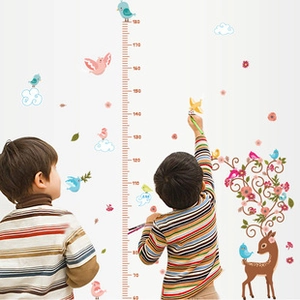 Detailed growth chart wall decal with forest animals being used by kids on white wall
