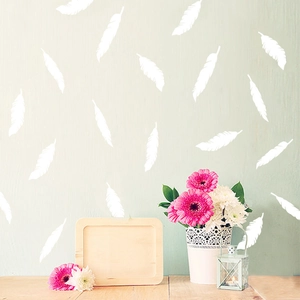 Detail showing various white feather wall decals on a soft green textured wall background