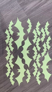 Flat lay of different sized light green bat wall stickers on a grey wood grain background