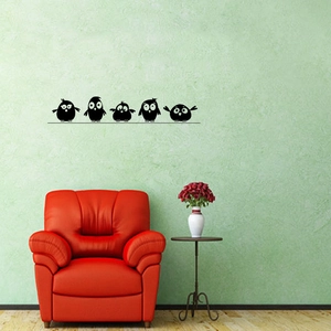 Minimalist black bird wall stickers on a green wall above a modern red sofa
