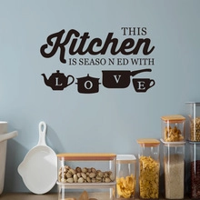Detail of black vinyl wall decal with Kitchen quote and cookware silhouettes on a blue wall
