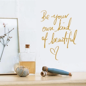 Détail du sticker mural 'Be your own kind of beautiful' avec écriture dorée et cœur