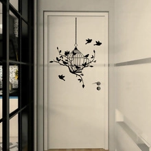Detail view of black birdcage and flying birds silhouette wall decals on white door