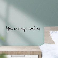 Detail of black 'You are my sunshine' wall decal sticker on a green bedroom wall surface