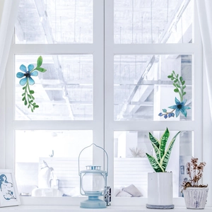Blue floral Christmas window stickers on glass pane with vintage lamp and houseplant