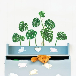 Détail de stickers muraux Monstera réalistes sur un mur rayé dans un décor de chambre