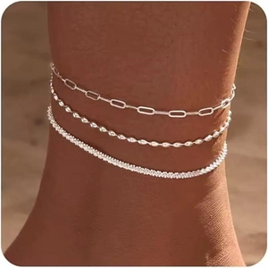 Three-piece silver anklet set featuring paperclip, bead, and rope chains on a sandy beach
