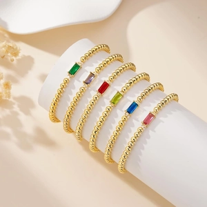 Lot de six bracelets à perles dorées avec pierres de naissance colorées sur un présentoir