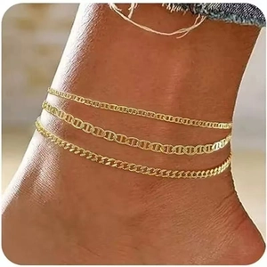 Close-up of golden multi-layered anklet set featuring flat link and cuban chain styles