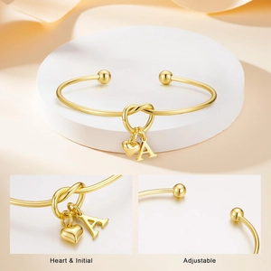 Bracciale a nodo in acciaio dorato con ciondoli a cuore e lettera A su base bianca