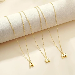 Polished gold initial necklaces featuring A, K, and M pendants on minimalist chains